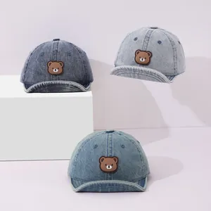Three shades of denim baby baseball caps with cute bear patches and soft flip brims