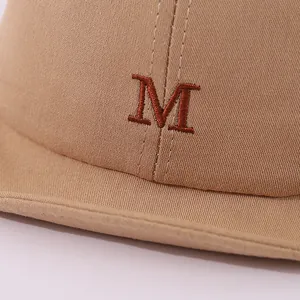 Detailed view of red M embroidery on khaki soft cotton twill baby baseball cap fabric