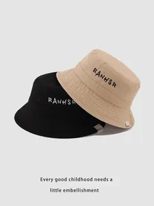 Close-up of embroidered RANHSR letters on cotton bucket hats in black and beige
