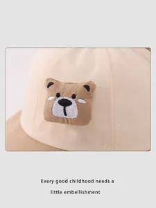 Gros plan sur un chapeau bob en coton beige avec bord marron et broderie d'ours en 3D