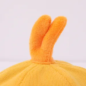 Vue détaillée du tricot jaune et du petit pompon orange sur le bob pour bébé