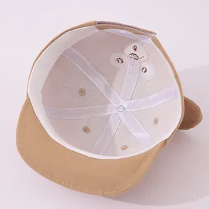 Detailed inner view of khaki baby baseball cap showing cotton lining and bear embroidery