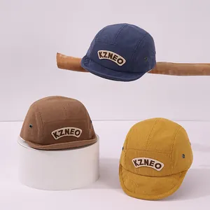 Détail de la texture en velours côtelé et broderie KZNEO sur les casquettes enfants