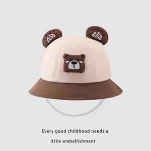 Détail du chapeau bob pour bébé avec oreilles d'ours, broderie et mentonnière élastique