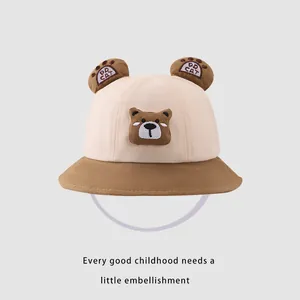 Détail d'un chapeau bob pour bébé bicolore avec oreilles d'ours et écusson mignon