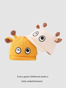 Détail de casquettes bébé jaunes et beige avec yeux de dessin animé et maille de coton