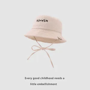 Detail of baby sun hat featuring RANHSR embroidery and adjustable beige chin strap