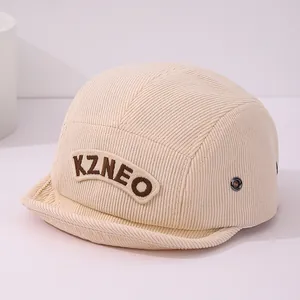 Détail macro du velours côtelé beige et de la broderie KZNEO sur la casquette pour enfant
