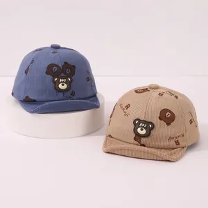 Détail de casquettes bébé en velours côtelé avec imprimés ours et patchs en bleu et beige