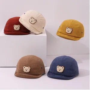Détail de cinq couleurs de casquettes en velours pour bébé avec écusson ours