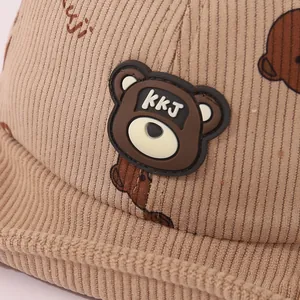 Détail du tissu en velours côtelé kaki avec un écusson d'ours en 3D sur la casquette bébé