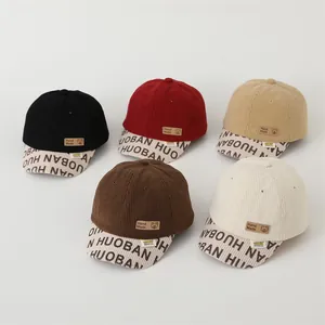 Close-up of assorted corduroy baseball caps for kids with hand-made leather patch and print