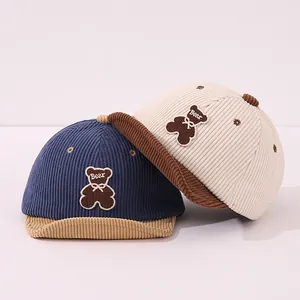 Détail des casquettes en velours côtelé pour bébé avec broderie d'ours en bleu et beige