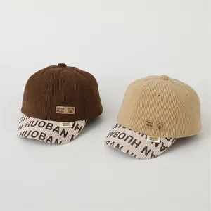 Detail of corduroy texture and bear leather patch on brown and beige baby baseball caps