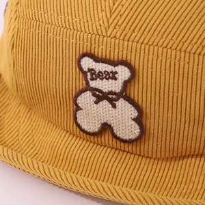 Détail de la casquette bébé en velours côtelé avec broderie ours et texture côtelée