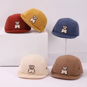 Vue détaillée de cinq bonnets en velours pour enfants avec écussons d'ours mignons