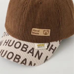 Macro shot of brown corduroy baseball cap showing fine texture and handmade leather patch