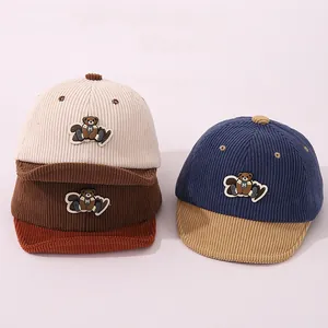 Détail du velours côtelé des casquettes pour bébé avec écusson ours et lettre M brodée