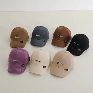 Dettaglio di sette cappellini in cotone colorato con ricamo 'me' ed etichette in tessuto