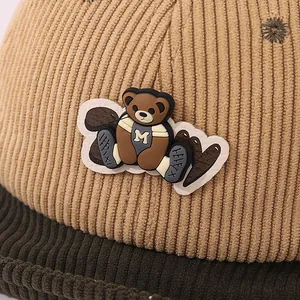 Détail macro du bonnet en velours côtelé pour bébé avec écusson ours en silicone 3D