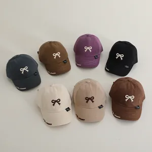 Flat lay of seven colorful cotton baseball caps for kids with 3D bow embroidery details