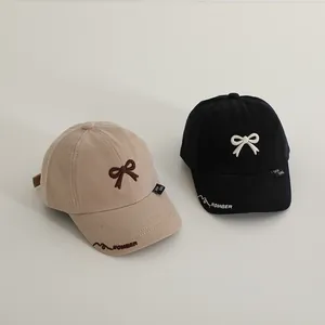Kids cotton baseball caps with bow embroidery in beige and black colors