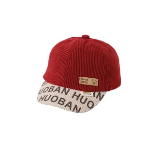 Kids corduroy baseball cap with red crown and cream brim featuring a handmade leather patch