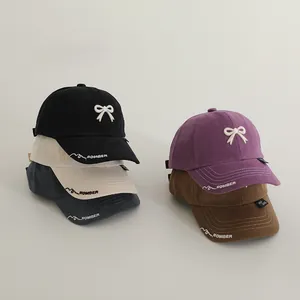 Close-up of assorted cotton baseball caps with bow embroidery and cursive lettering