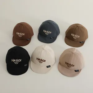 Detail of baby baseball caps with Hello embroidery and soft brims in various earth tones