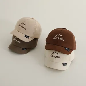 Close-up of four kids' cotton baseball caps in beige and brown colors with mountain embroidery