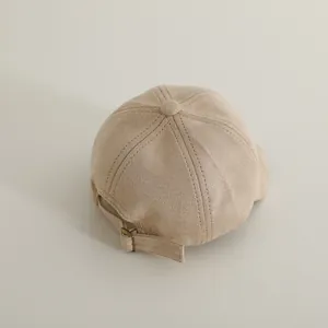 Detail view of the soft suede texture and bronze metal buckle on children baseball cap