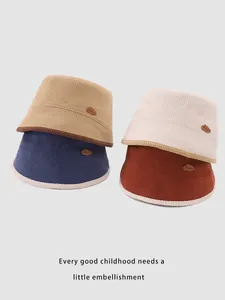 Dettaglio di cappelli a secchiello in velluto a coste per bambini nei colori kaki e crema