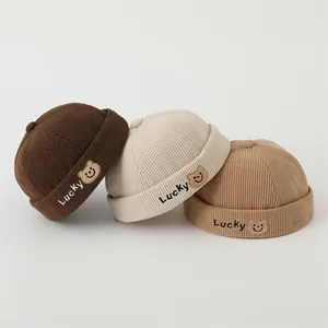 Three corduroy docker hats with Lucky bear embroidery in brown, beige, and khaki colors