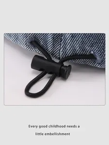 Detail of blue denim cap with black elastic drawstring and plastic spring toggle