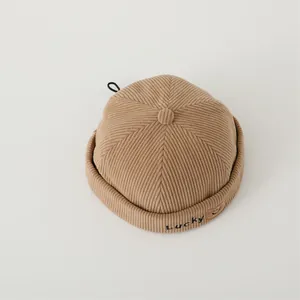 Detail of corduroy baby beanie with Lucky embroidery and smiley face on rolled brim