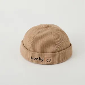 Detail of khaki corduroy skullcap with Lucky embroidery and cute bear label for kids