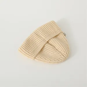 Detailed view of beige ribbed knit beanie with soft texture and small side woven label
