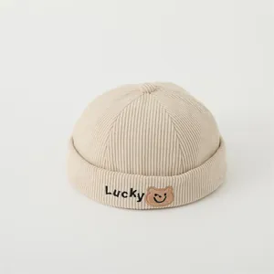 Detailed close-up of corduroy texture and Lucky bear embroidery on the beige skull cap