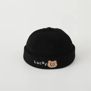 Close-up of black corduroy baby beanie with Lucky embroidery and a brown bear patch