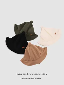 Detail view of corduroy toddler bucket hats with pom-poms in four earthy colors