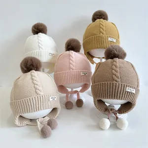 Detailed knit texture and plush pom-poms on earflap winter hats for toddlers