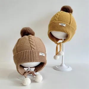 Winter knit baby earflap hat with thick pom-poms for children aged two to four
