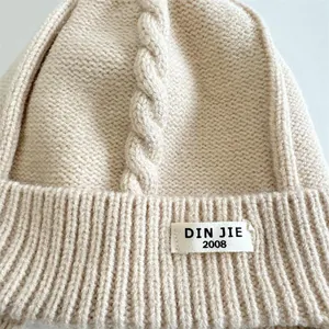 Detailed view of beige cable-knit texture and rib-knit edge on a warm baby winter hat