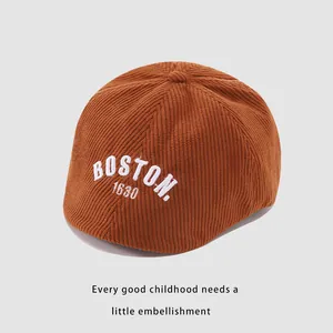 Detalle de textura de pana marrón oscuro y bordado blanco BOSTON en boina para niños