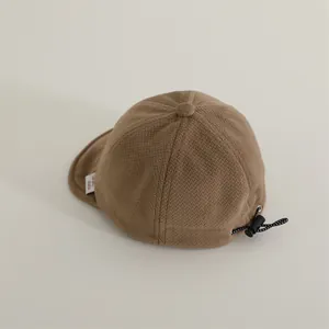 Detail of waffle-knit baby cap showing the adjustable elastic drawstring for custom fit