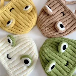 Flache Ansicht von gestrickten Frosch-Mützen in Gelb, Braun, Weiß und Grün mit Rippmuster
