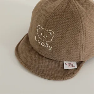 Detailed close-up of brown waffle cotton baby cap with bear and Lucky embroidery