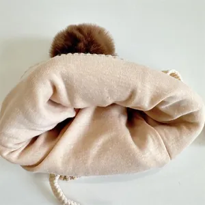 Winter beige knit hat for kids with large brown faux fur pom pom and warm earflaps
