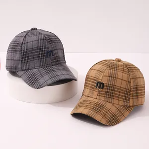 Close-up of checkered plaid baseball caps with embroidered letter M in wool fabric