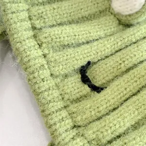 Detaillierte Makroaufnahme der grünen Stricktextur und des Froschauges auf dem Hut